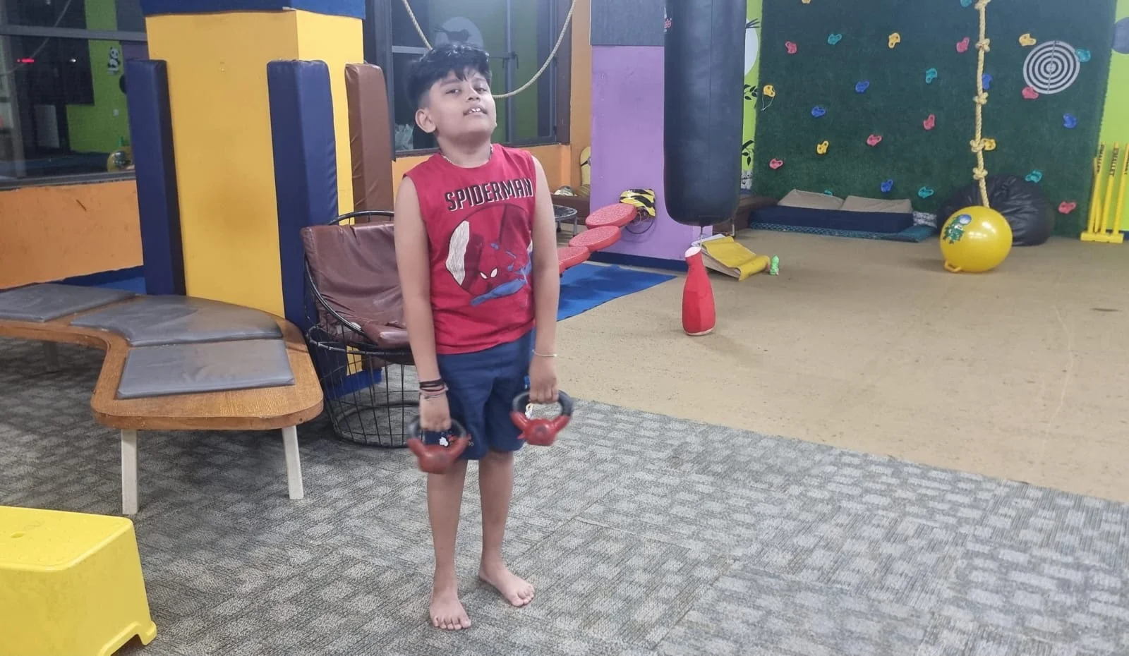Young child at a Jump-n-rise , kids fitness center lifting weights safely