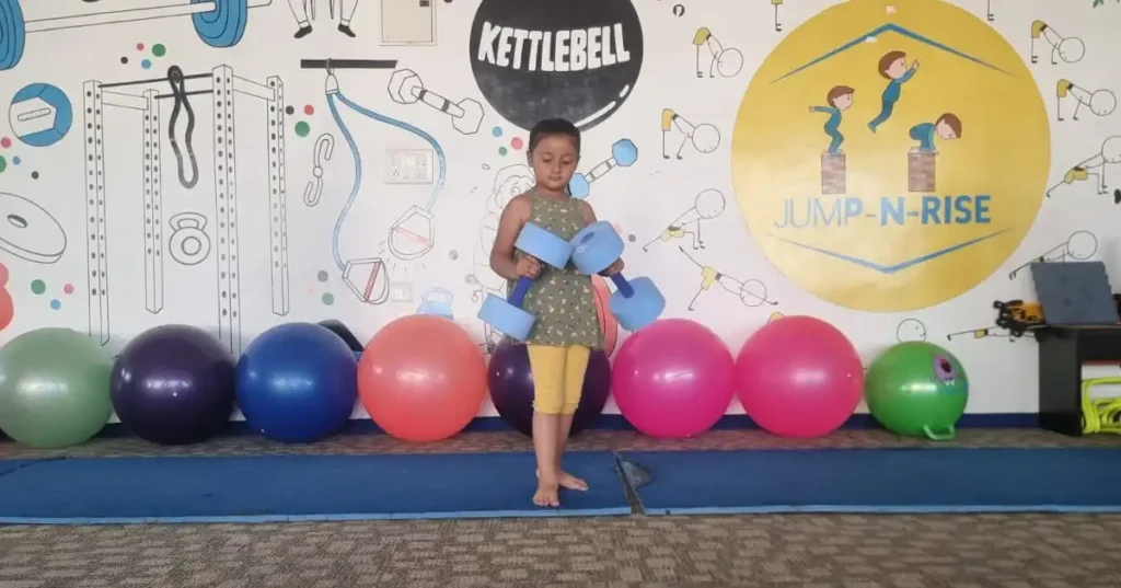 A young child at Jump-n-Rise gym, standing with exercise equipment, illustrating a blog post about the impact of gym activities on height growth in children.