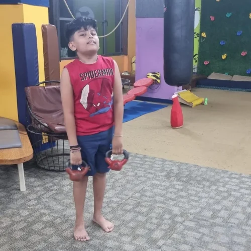 Young child at a Jump-n-rise , kids fitness center lifting weights safely