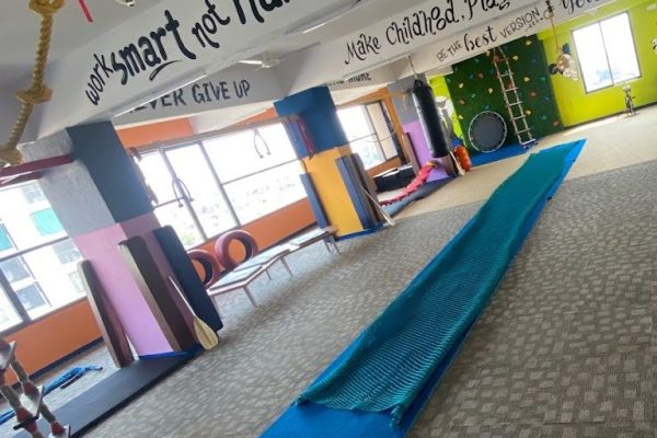 View of the empty indoor play space at Jump-n-Rise with colorful equipment.